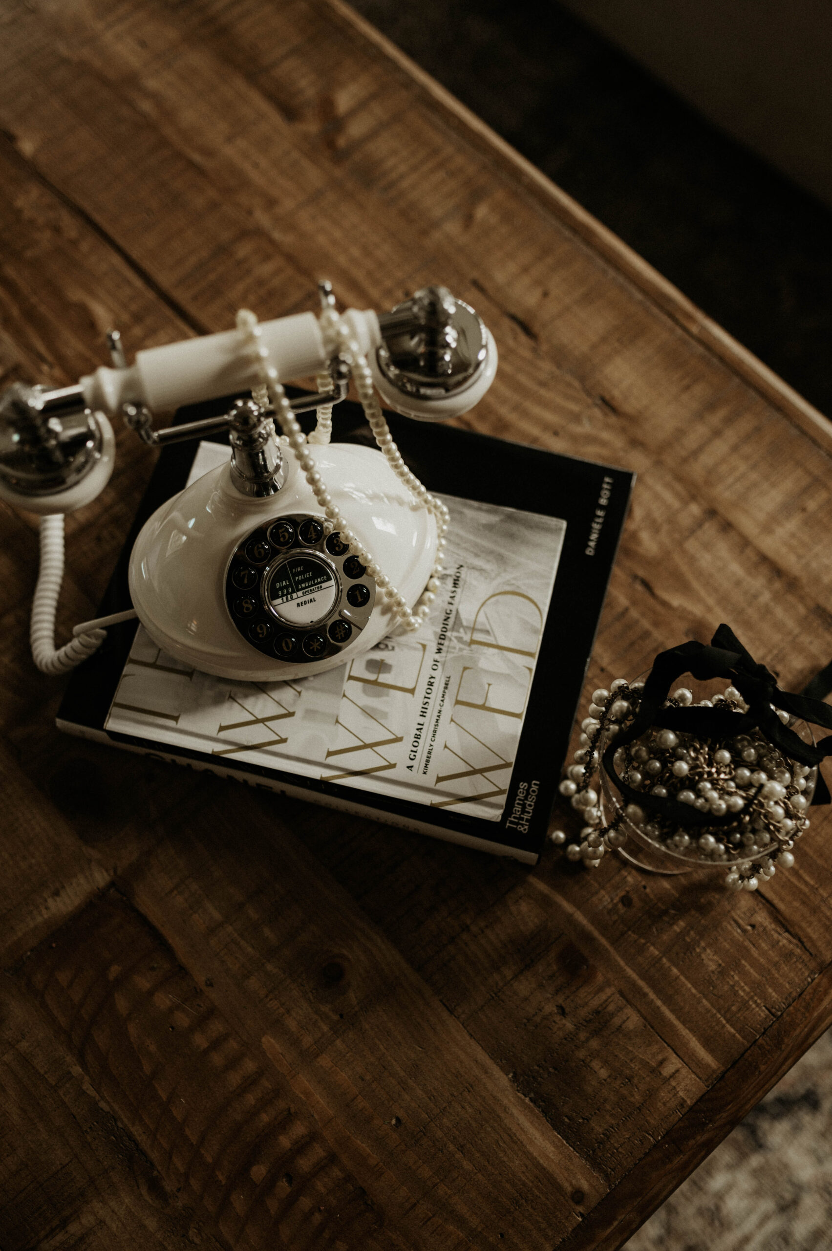 A white rotary phone sitting on a wedding magazine