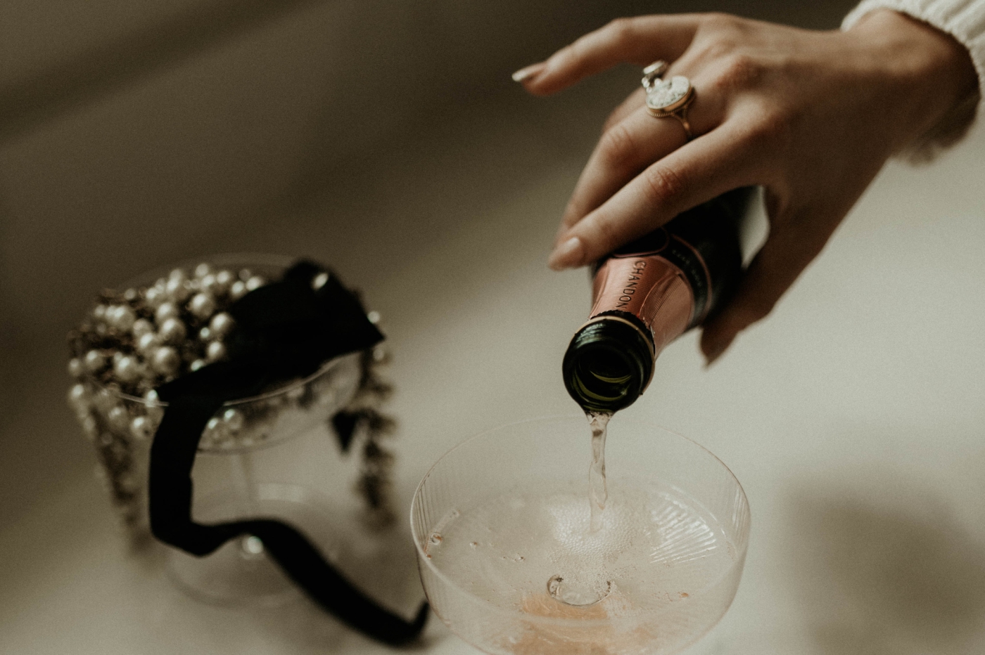 A close shot of a woman's hand while she pours champagne into a glass