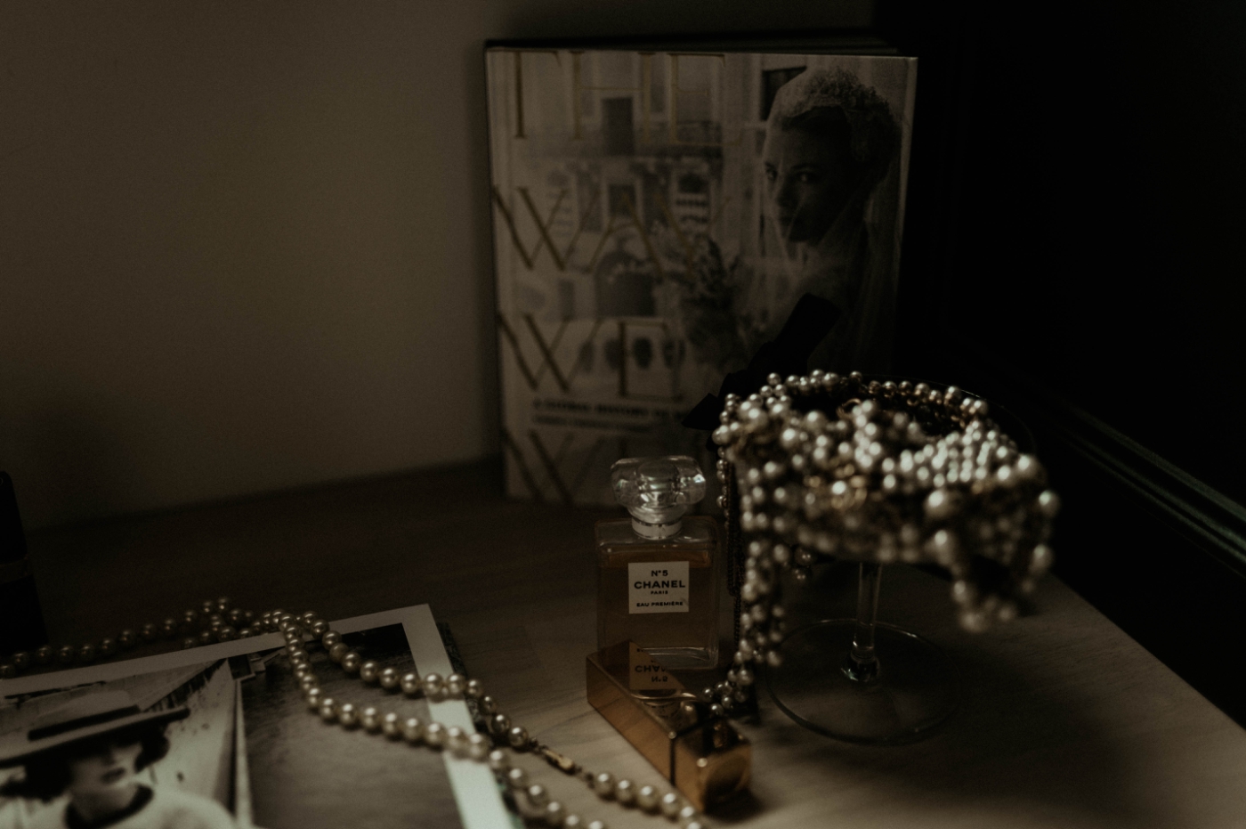A dark, filmy photo of a pearl necklace in a chamapagne glass